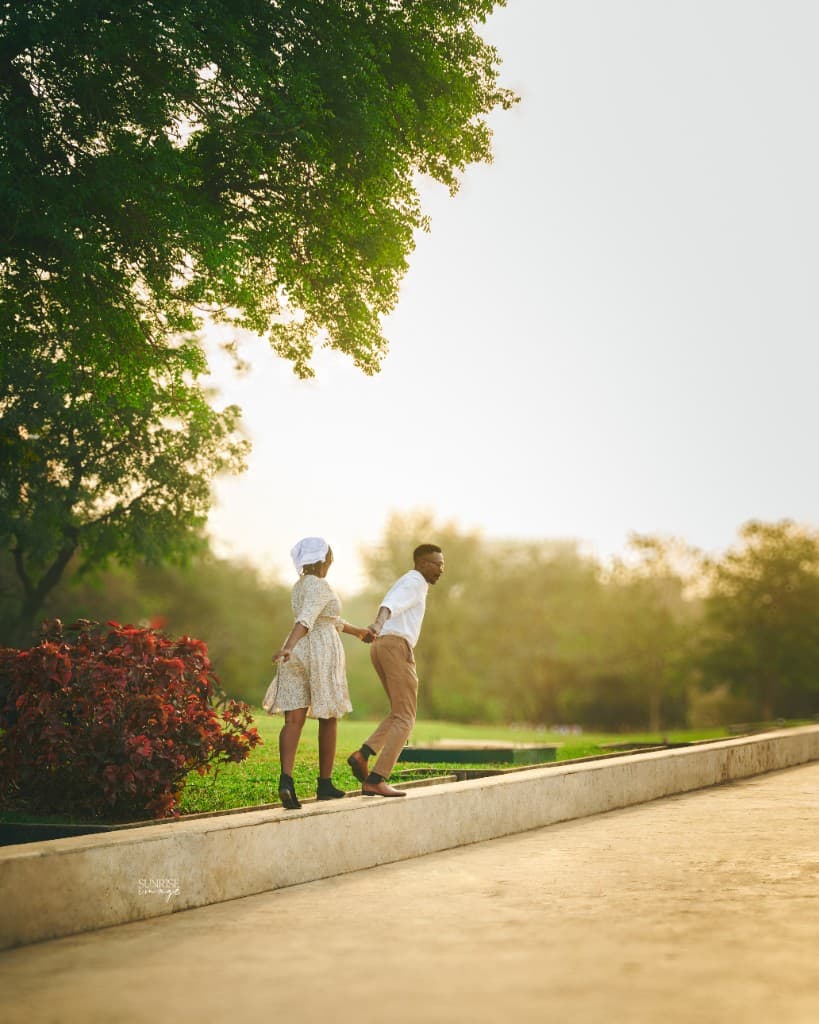 Couple walking hand in hand along a park wall at golden hour, Sunrise Image photography